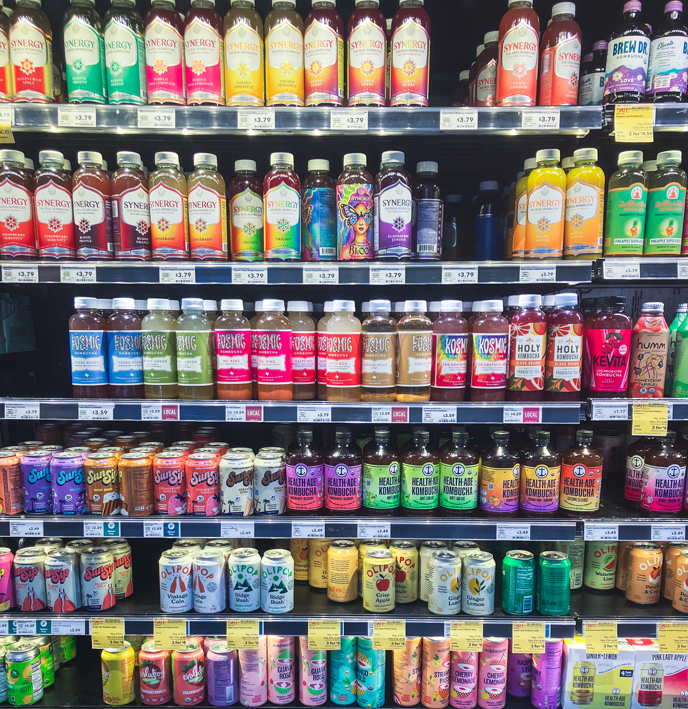 Retail shelf of Kombucha brands with multi-colored packaging.
